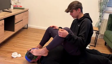German master sitting on feet licking boy